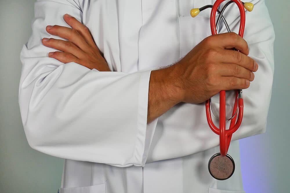 Doctor in lab coat holding red stethoscope